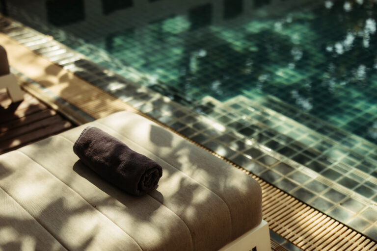 An inviting poolside sun lounger prepared with a fresh towel, ready for guests to relax at Athena Hotel Pakse.