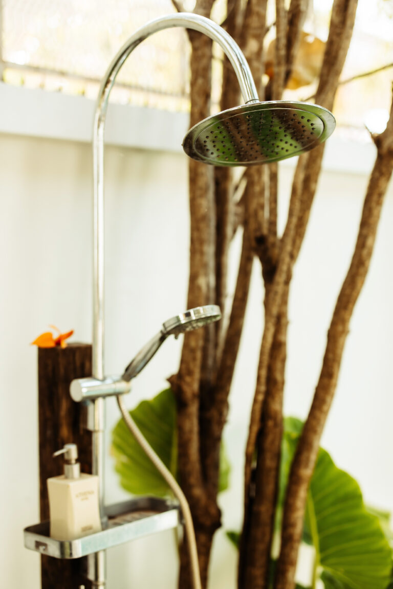 A unique, nature-inspired shower design at Athena Hotel Pakse, featuring a rain shower head set against a wall of natural wood branches.