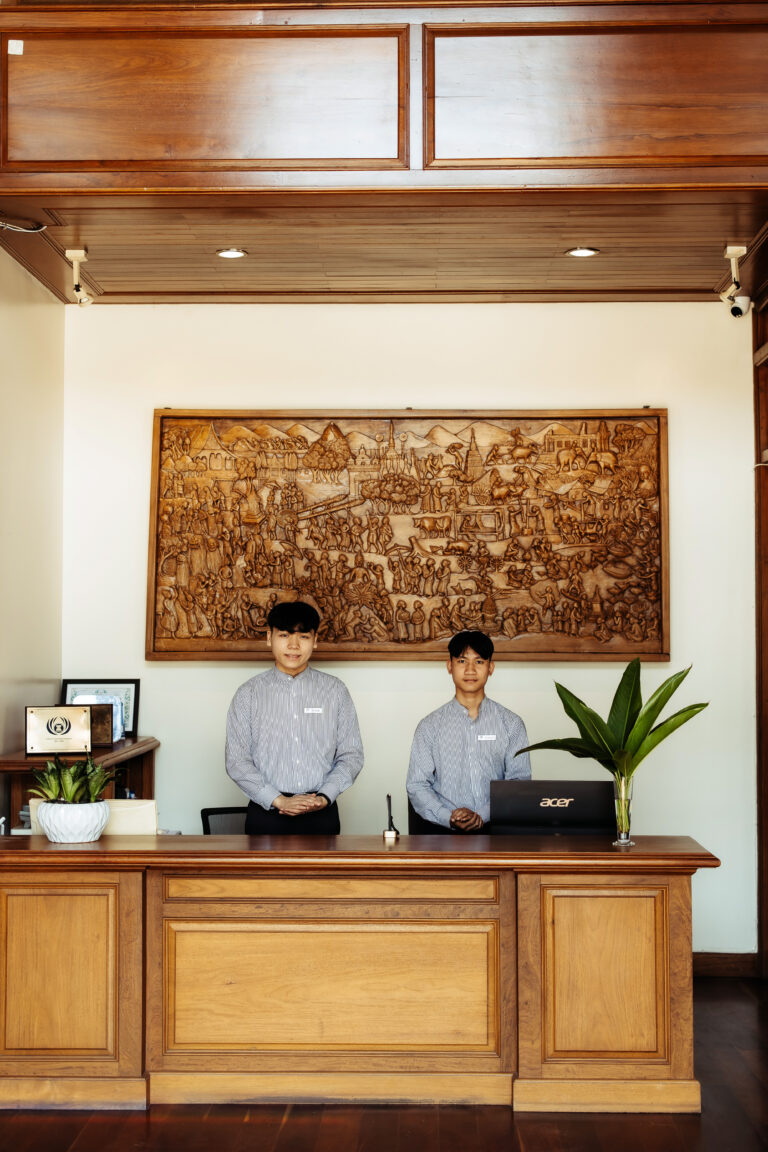 The welcoming reservation desk at Athena Hotel Pakse, with two professional staff attending to guest services.
