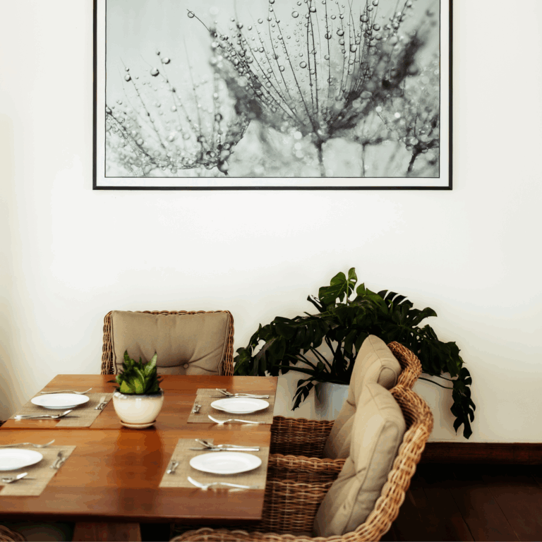 An elegant dining area featuring a set table, comfortable rattan chairs, and modern black and white art on the wall.