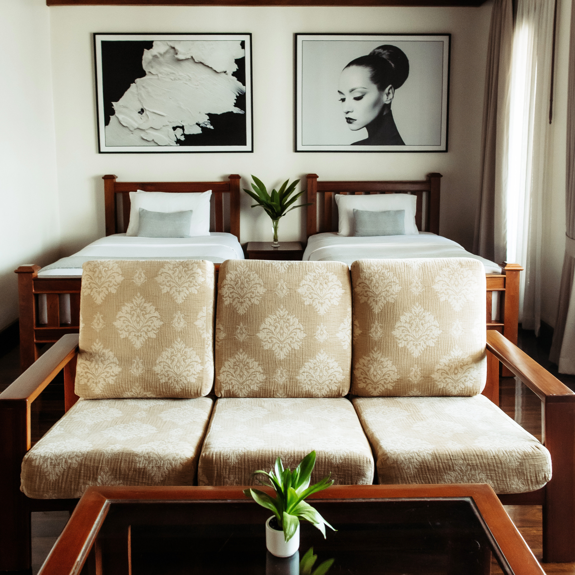 Elegantly decorated twin room at Athena Hotel Pakse, with classic wooden furniture and unique black and white art above the beds.