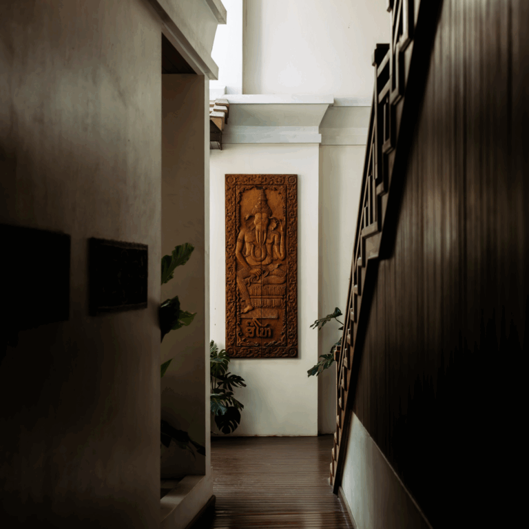 The elegant interior corridor of Athena Hotel Pakse, featuring dark wood floors, a staircase, and traditional artwork.